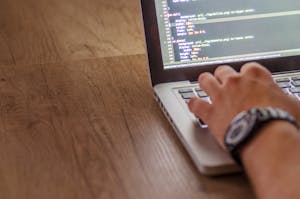 Close-up of a person coding on a laptop, showcasing web development and programming concepts.